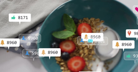 Food notification icons hovering over teal bowl with granola, berries and metal spoon on table. Food, breakfast, healthy, natural, vibrant, minimalistic, lifestyleの写真素材