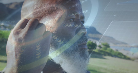 Senior man adjusting wireless earbud in park, with semi-transparent virtual interface overlay. Technology, innovation, connectivity, outdoors, wellness, leisure, modernの写真素材