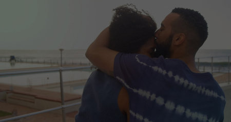 Kissing couple wearing casual attire leaning on metal railing at seaside promenade, copy space. Romantic, waterfront, lifestyle, serene, candid, emotional, scenicの写真素材