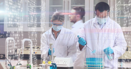 Lab scientists in coats and gloves pipetting blue solution into tube rack in lab, with micropipette. Science, research, laboratory, experimentation, precision, innovation, technologyの写真素材