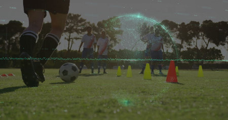 Player dribbling soccer ball on pitch at dusk, with cones, shin guards and cleats, copy space. Athletics, sports, teamwork, outdoor, training, fitness, motivationの写真素材