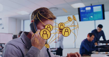 Holding desk handset, man wearing shirt showing network graphic near screens in office, copy space. Collaboration, communication, connectivity, teamwork, modern, professional, digitalの写真素材