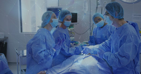 Surgical team performing surgery in operating room, with sterile blue gowns, masks and scalpels....