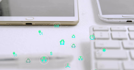 Displaying white tablet sitting on desk, showing eco icons over smartphone, keyboard, copy space....