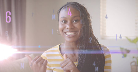 Woman in yellow striped shirt giving thumbs up on living room couch, lens flare and overlays. Cheerful, positivity, technology, casual, relaxation, modern, interiorの写真素材