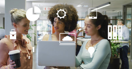 Discussing details on laptop three-woman team in open office, with coffee cup and floating icons....