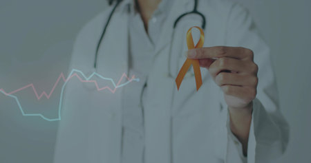 Doctor wearing lab coat and stethoscope holding orange ribbon in studio, with floating line graphs....