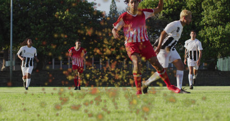 Red-and-white jersey soccer player kicking on grass field, with cleats, turf fragments spraying. Athletic, sport, teamwork, outdoors, competition, fitness, vitalityの写真素材