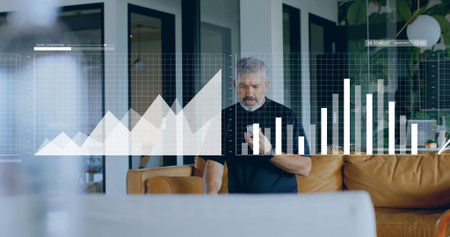 Viewing holographic charts senior man holding smartphone in modern living area, with leather sofa. Professional, innovation, digital, sophistication, relaxation, contemporary, smart technologyの写真素材