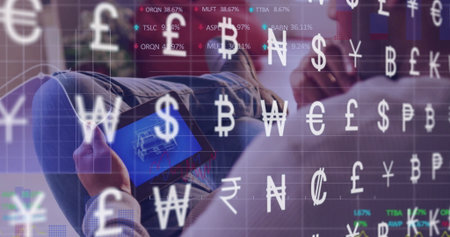 Reclining Asian man analyzing schematic on tablet in lounge, with floating currency symbols. Finance, technology, digital, innovation, professional, modern, data visualizationの写真素材