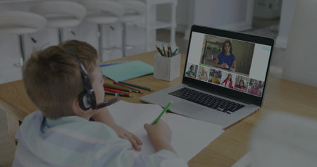 Studying boy wearing striped shirt and headset at kitchen table with laptop, pencils, copy space....