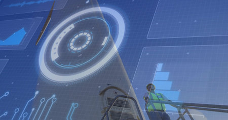 Worker wearing safety vest and hat examining digital interface on platform at job site, copy space. Industrial, technology, innovation, construction, futurism, digital, engineeringの写真素材