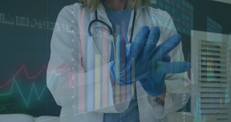 Provider in white coat blue scrubs and stethoscope pulling on gloves in clinic with digital charts. Medical, healthcare, diagnostics, technology, professionalism, science, hospitalの写真素材