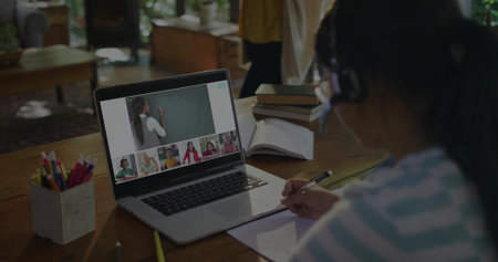 Taking notes, Asian girl wearing striped shirt, headset at home study desk, with laptop, copy space. Education, e-learning, remote, technology, learning, classroom, studyingの写真素材