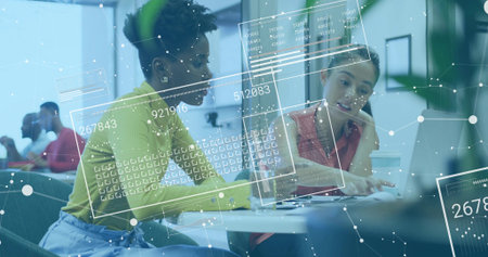 Collaborating two coworkers reviewing documents, typing on laptop in open-office with glass walls. Collaboration, teamwork, modernoffice, dataanalytics, innovation, professional, creativeの写真素材