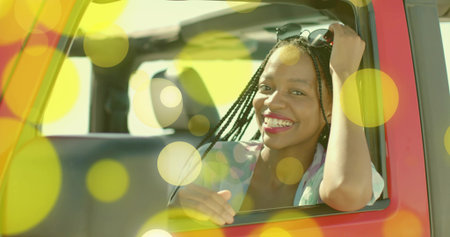 Smiling woman sunglasses on head leaning out of red convertible at roadside, roll bar, copy space....