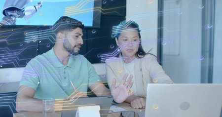 Tech professionals analyzing data using laptop in office, with stylus and robotic arm. Innovation, collaboration, digital, futuristic, enterprise, workspace, technologyの写真素材