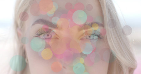 Displaying adult female face featuring translucent pastel circle overlays in studio, bokeh effect....