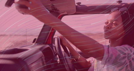 Adjusting mirror, woman driver cruising in red convertible on desert highway, copy space. Adventure, freedom, lifestyle, outdoor, minimalistic, vibrant, travelの写真素材