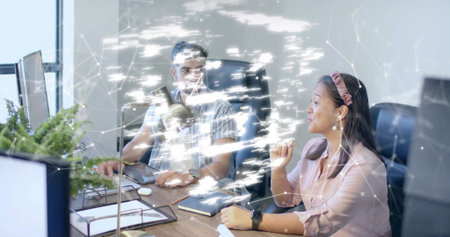 Reviewing documents colleagues gesturing and analyzing in office with digital overlay and plant. Business, workspace, technology, collaboration, productivity, modern, corporateの写真素材