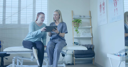 Prosthetic leg patient and therapist discussing exercise using tablet in clinic, with muscle charts....