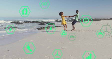 Spinning couple holding hands on sandy beach near waterline, with scattered rocks and footprints. Romance, leisure, harmony, serenity, outdoor, lifestyle, vibrantの写真素材