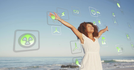 Extending arms, woman in white dress standing on sandy shore, energy icons floating, copy space....