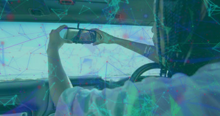 Woman using smartphone checking reflection in cabin, sun visor mirror, steering wheel, copy space. Luxury, interior, casual, modern, technology, lifestyle, comfortの写真素材