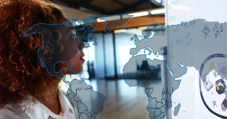 Analyzing woman in white blouse writing formulas on board in office, map and cube, copy space. Innovation, intelligence, strategy, collaboration, professionalism, modernity, analyticalの写真素材