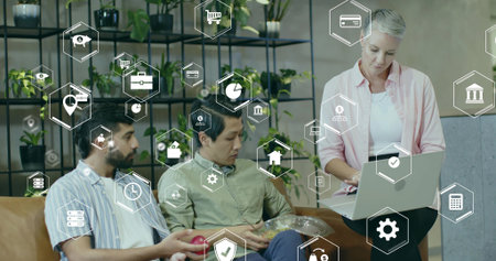 Three professionals reviewing printed charts on laptop in office lounge, with digital finance icons....