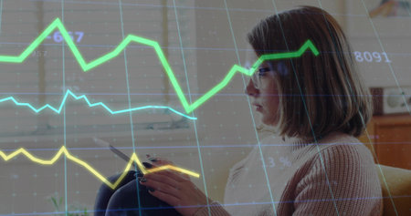 Interacting woman holding tablet, tracing graph overlays on window blinds in lounge, copy space. Technology, remote work, modern, analytical, home office, professional, digitalの写真素材