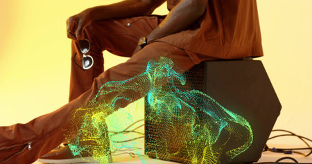 Sitting sideways man wearing rust outfit on black box in studio, with glowing wireframe projection....