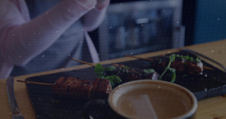 Displaying black plate holding grilled meat skewers garnished with greens at restaurant with sauce. Gourmet, culinary, rustic, dining, hospitality, food presentation, casualの写真素材