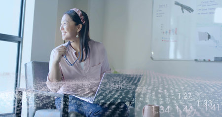 Smiling Asian woman wearing pink blouse gazing out window in office, with laptop digital overlay....