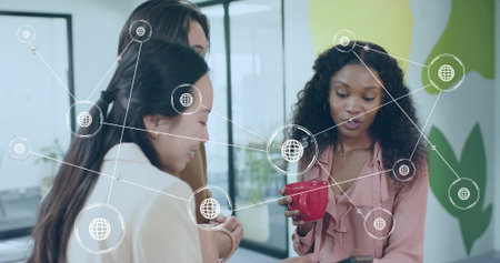Leaning three business casual colleagues viewing smartphone at office space, with red coffee mug. Collaboration, innovation, teamwork, modern, professional, vibrant, workspaceの写真素材