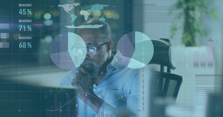Studying male wearing glasses and shirt analyzing charts on computer monitor at office desk. Business, analytics, data, technology, productivity, modern, corporateの写真素材