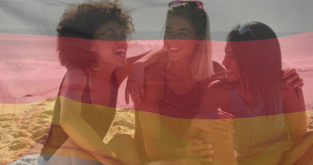 Smiling group linking arms sitting on shoreline under shade cloth, with beach towel and sunglasses. Friendship, leisure, relaxation, outdoor, vibrant, carefree, lifestyleの写真素材