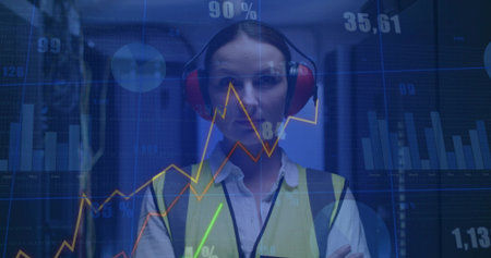 Technician wearing yellow vest red earmuffs inspecting racks in server room, floating data overlays. Professional, technology, data, monitoring, industrial, futuristic, analyticalの写真素材
