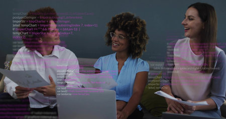 Three colleagues wearing shirts reviewing reports in office lounge with laptop and code snippets. Collaboration, teamwork, innovation, modern, professional, technology, workplaceの写真素材