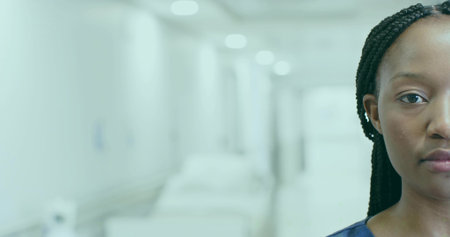 Standing nurse wearing blue scrubs in hospital corridor, with beds and overhead lights, copy space. Medical, healthcare, professional, clinical, modern, sanitation, teamworkの写真素材