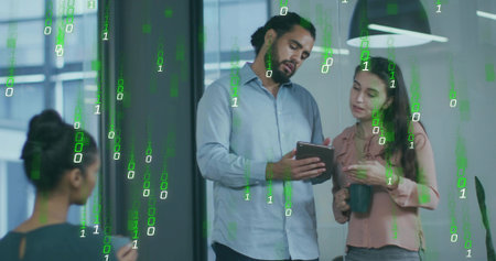 Collaborating office professionals examining tablet in workspace, with mugs and green binary code. Technology, teamwork, innovation, modernity, communication, data, workspaceの写真素材