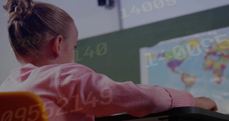 Girl student wearing sweater sitting at desk in class facing chalkboard with world map, copy space....