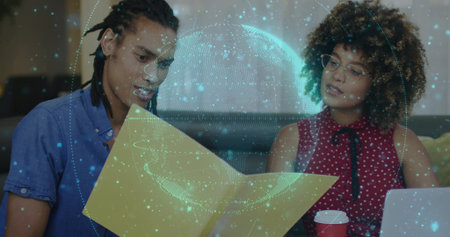 Pair in business attire reviewing folder and watching holographic globe in office lounge, laptop....