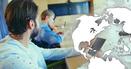Bearded man holding tablet with stylus at conference room table with world map overlay, copy space....