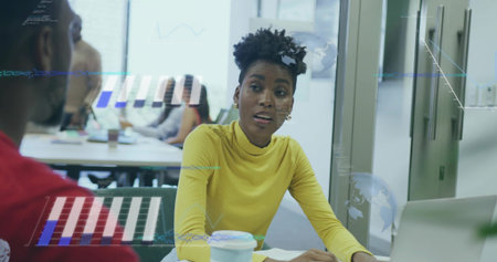 Talking woman wearing mustard top explaining data overlays at office meeting room, with laptop....