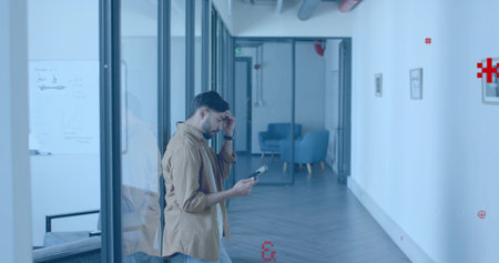 Walking Indian man wearing shirt and jeans holding tablet in glass corridor, with whiteboard....