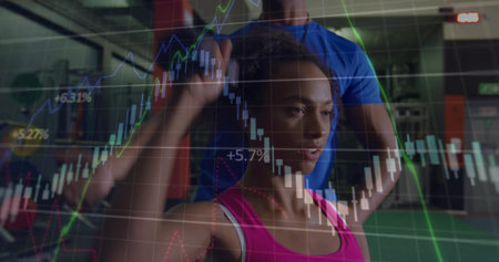 Lifting woman in pink top leggings curling dumbbell with coach in gym overlaying financial charts....