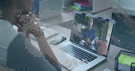 Displaying man on laptop screen holding papers at home office desk, with world map graphic....