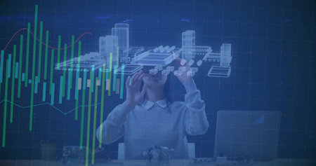 Engineer manipulating holographic building at desk with VR headset, bar charts, laptop, electronics....