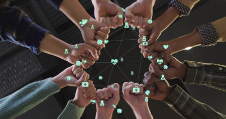 Forming circle of fists in sweaters and plaid shirts in atrium connecting green network icons. Collaboration, teamwork, connectivity, diversity, unity, digital, engagementの写真素材